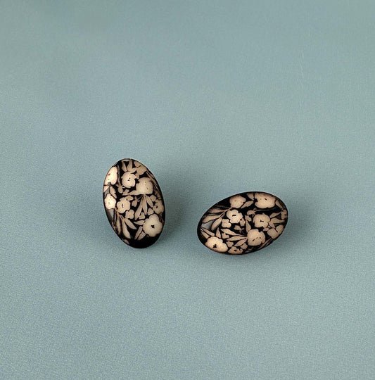 Pair of earrings with a decorative engraved design on a ivory surface