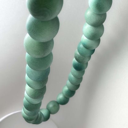 Close-up of a green beaded necklace on a white background